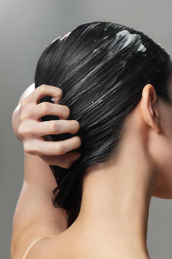 Ragazza applica la maschera rinforante per i capelli alla centella asiatica e peptidi, del marchio Some by Mi. 